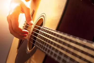 hand playing an acoustic guitar